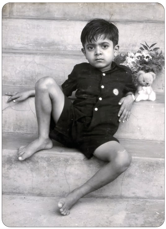 Promesse as a child sitting on the steps, with the same Teddy beside him