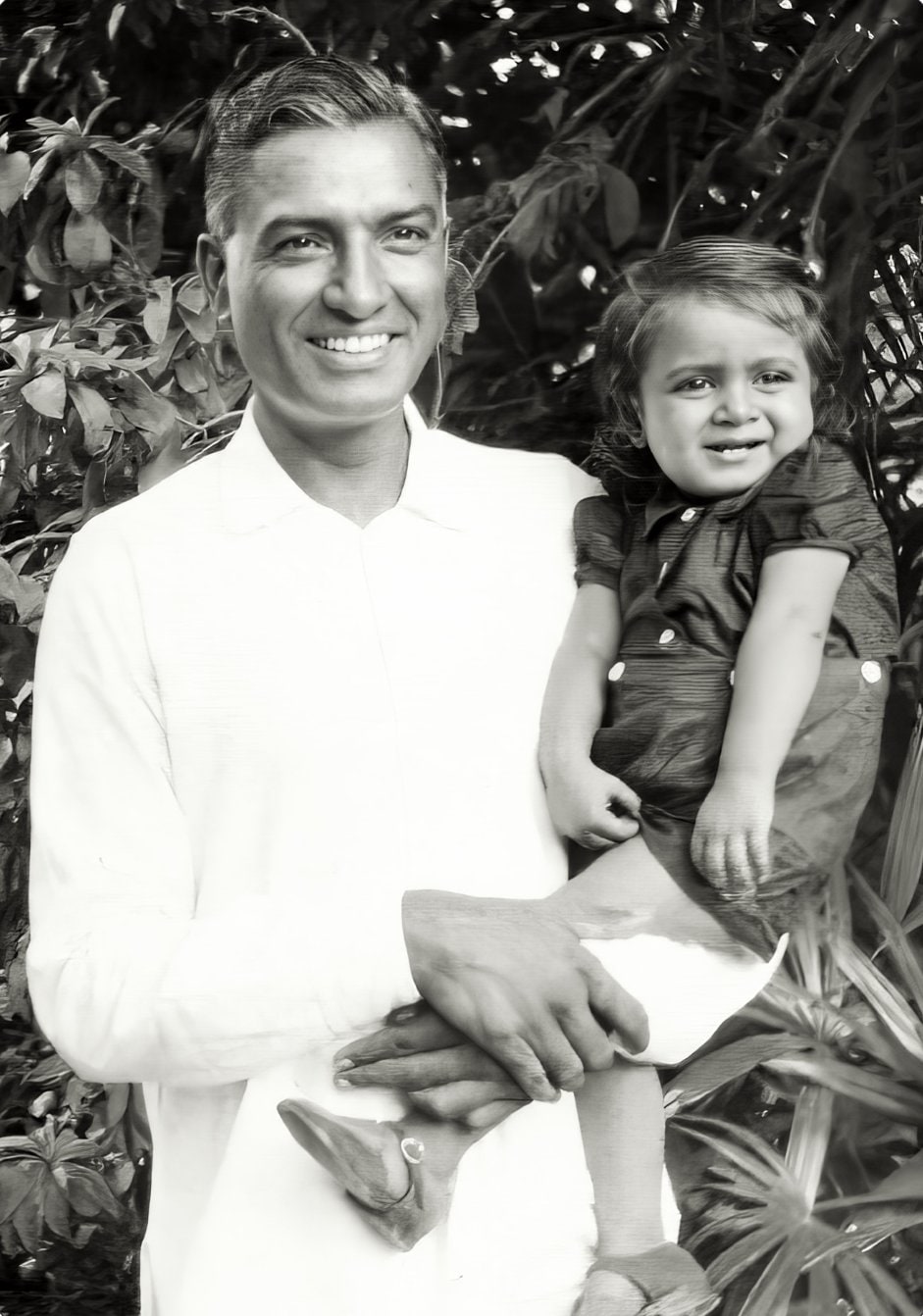 A young Surendranath Jauhar holding his little son Promesse in his arms, in a garden