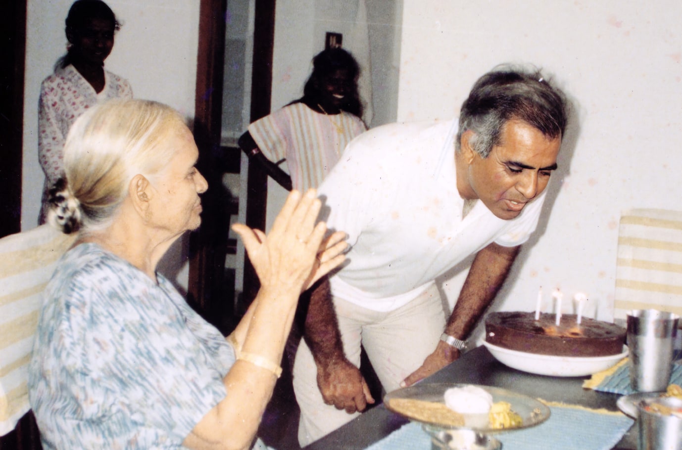 Promesse blowing out the candles on his birthday cake as his mother watches