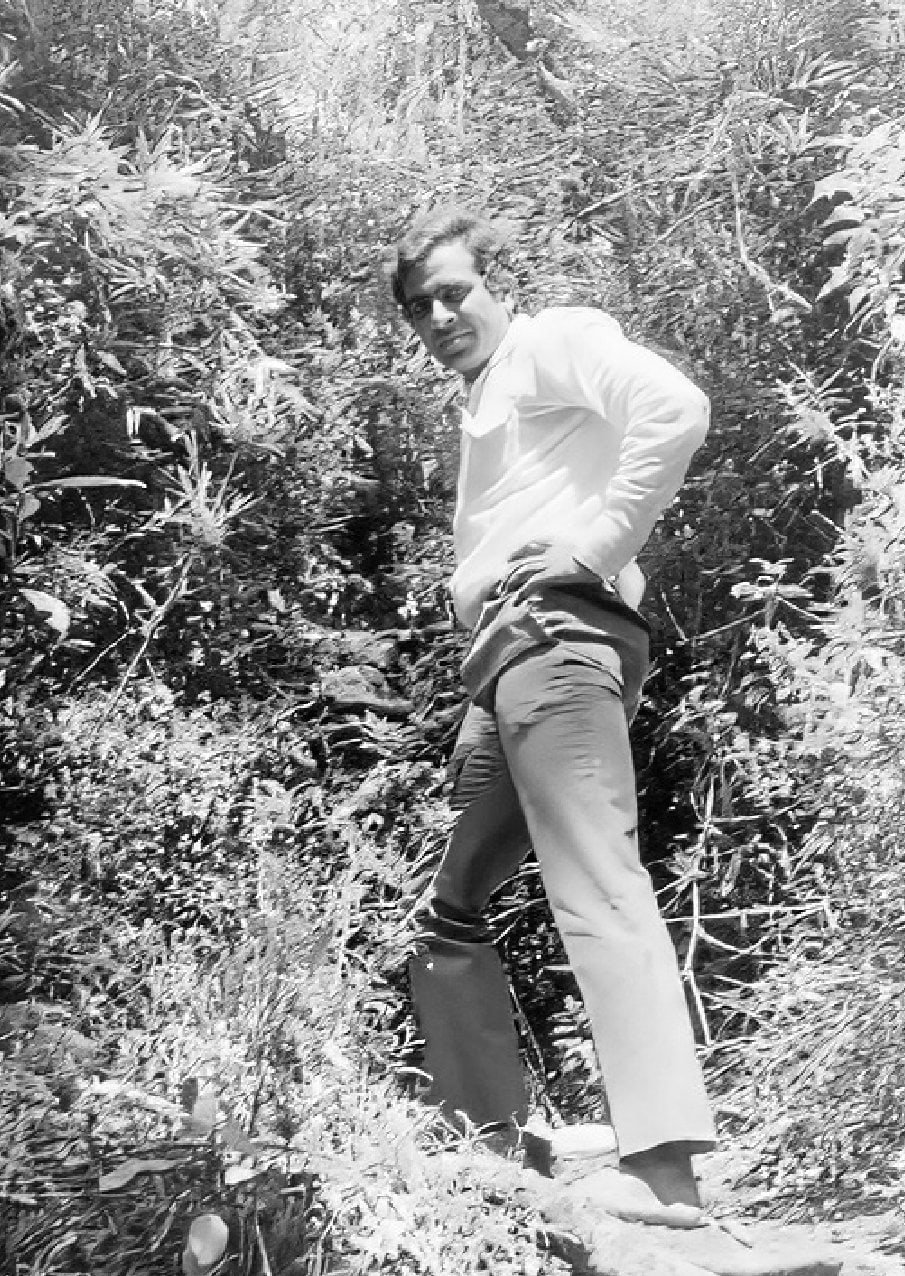 Promesse standing amid greenery on his travels